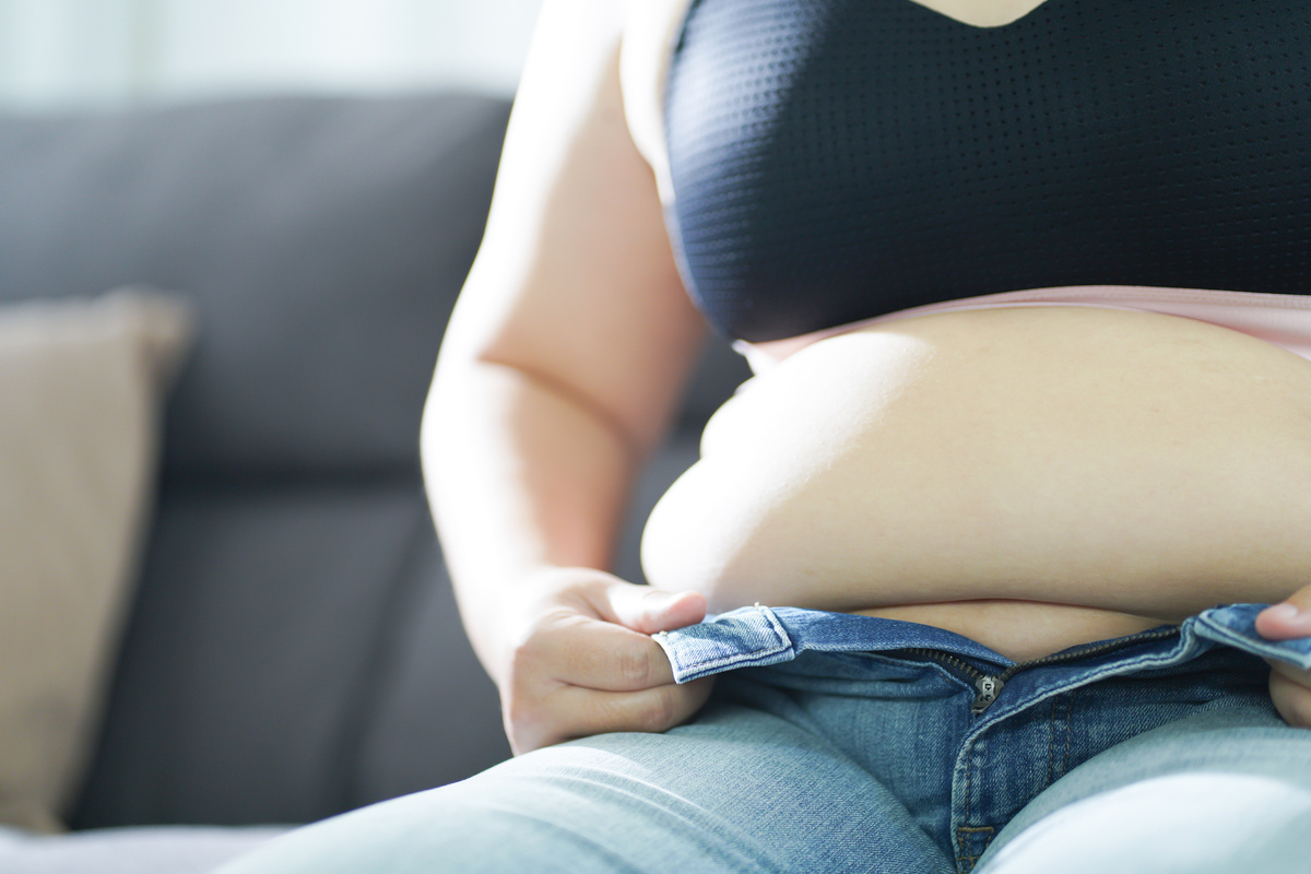 Obese Woman with fat upset about her belly. Overweight woman touching his fat belly and want to lose weight. Fat woman with tight clothing worried about weight diet lifestyle concept